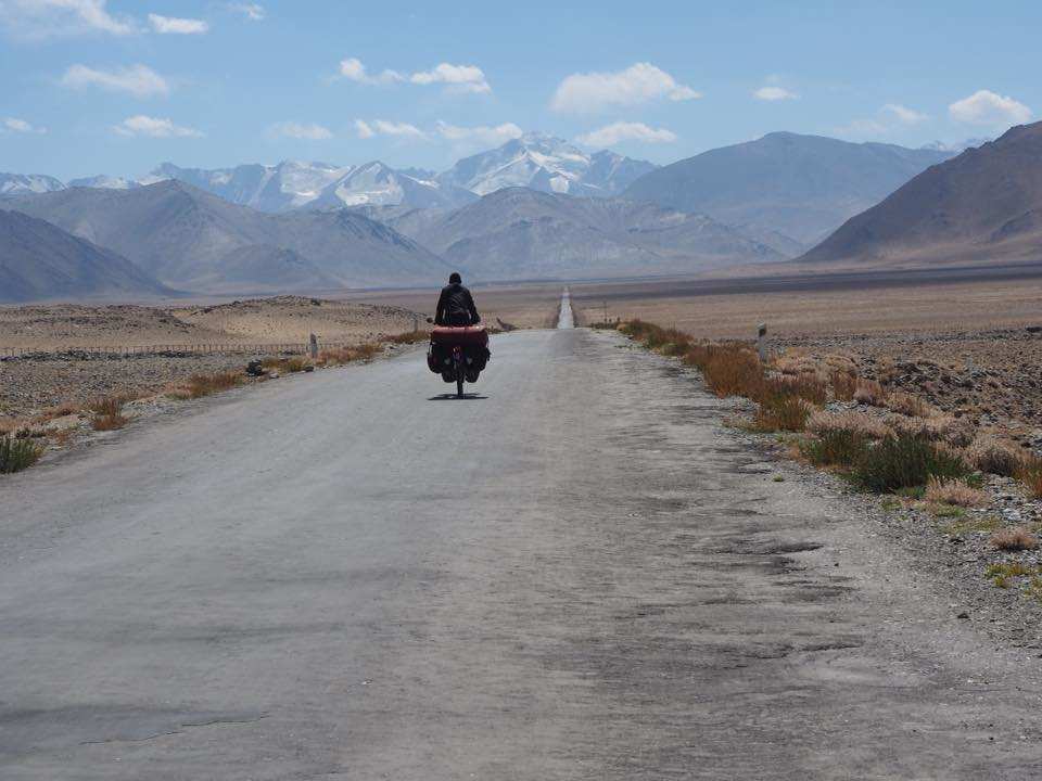 Ein einzelner Radfahrer auf einer breiten Piste vor einer Berglandschaft (Quelle: privat)
