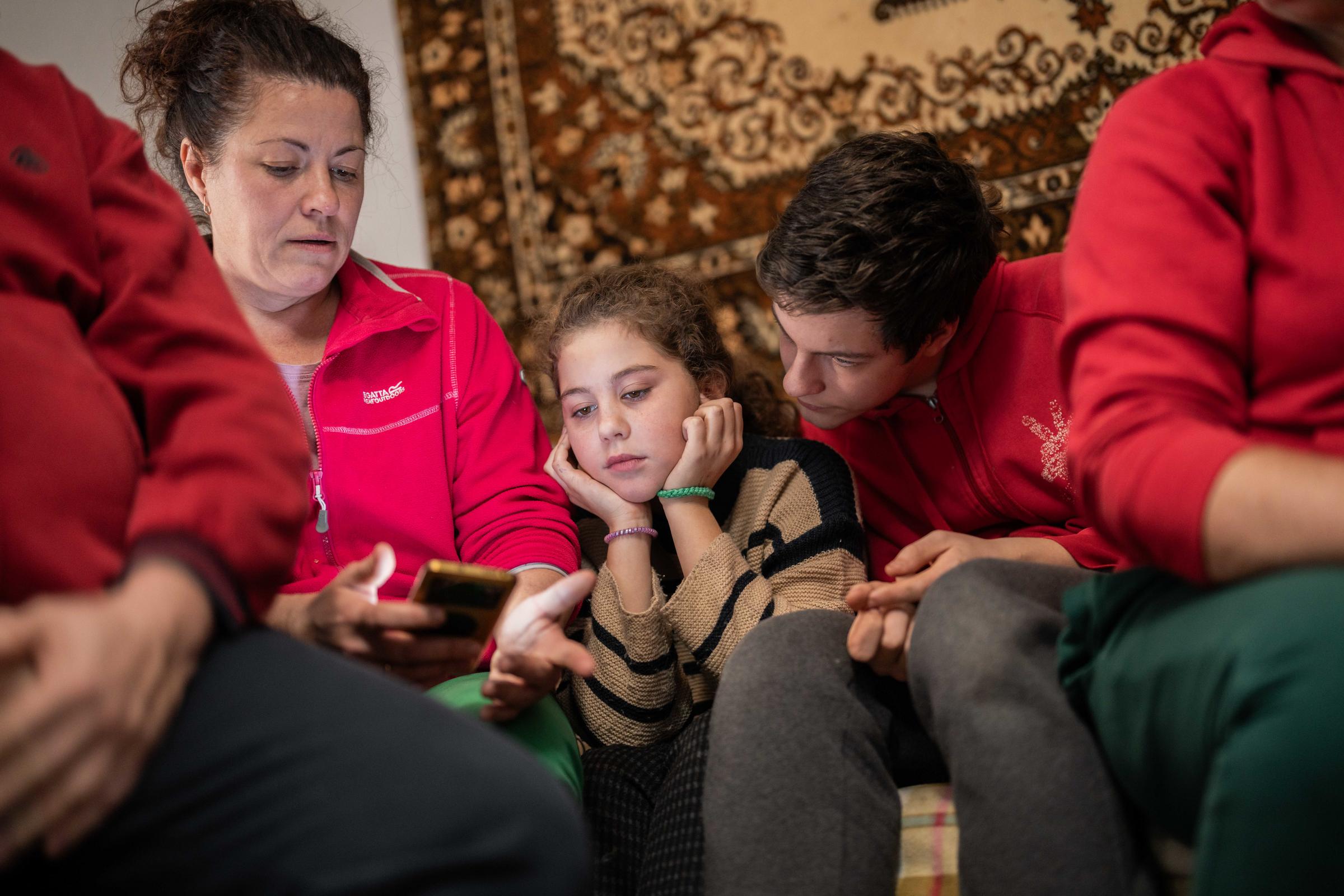 Ukrainische Mutter schaut mit ihrer Tochter und ihrem Sohn auf ihr Handy (Quelle: Jakob Studnar / Kindernothilfe)