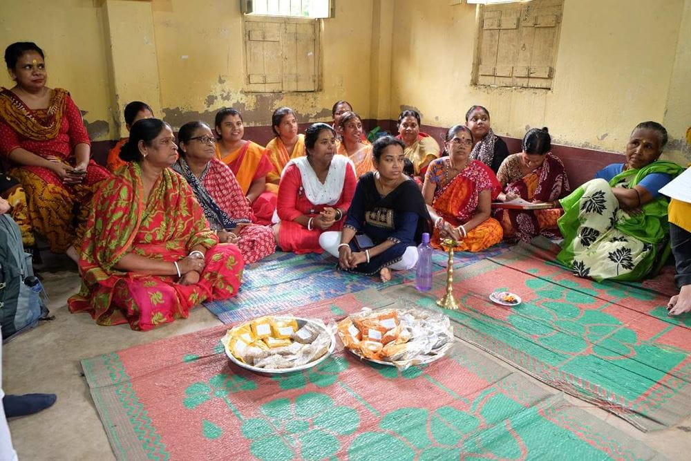 Indische Frauen sitzen auf dem Boden, vor ihnen auf 2 Tellern liegen Gewürztütchen (Quelle: privat)