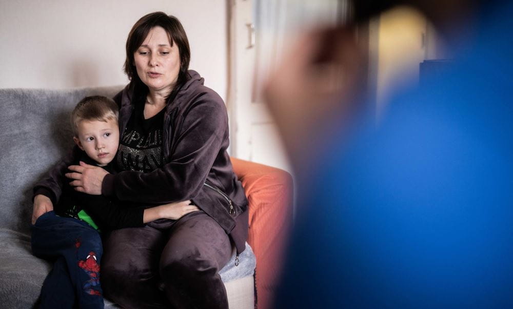 Eine Mutter sitzt auf einem Sofa und hält ihren Sohn im Arm (Quelle: Jakob Studnar) Eine Mutter sitzt auf einem Sofa und hält ihren Sohn im Arm (Quelle: Jakob Studnar)