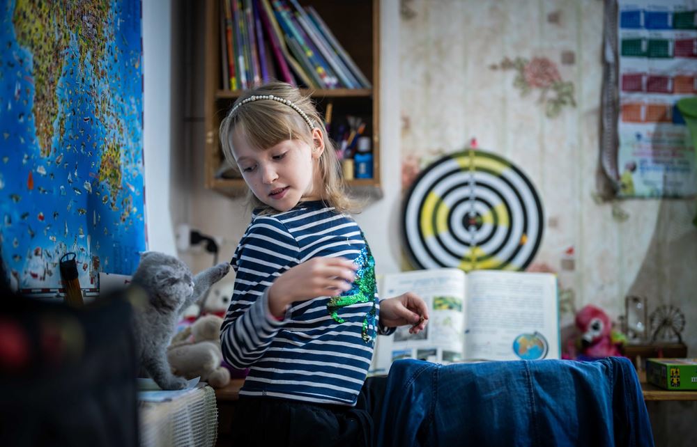 Eine kleine Katze zieht ein Mädchen am Pullover (Quelle: Jakob Studnar/Kindernothilfe)