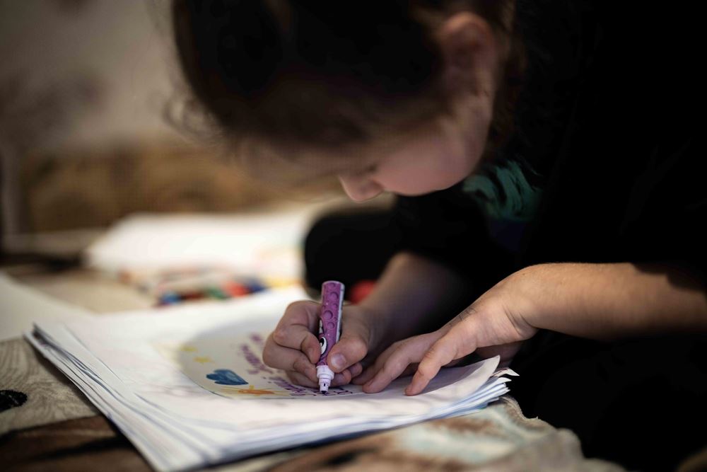 Ein Mädchen beugt sich über ein Blatt und malt (Quelle: Jakob Studnar/Kindernothilfe)