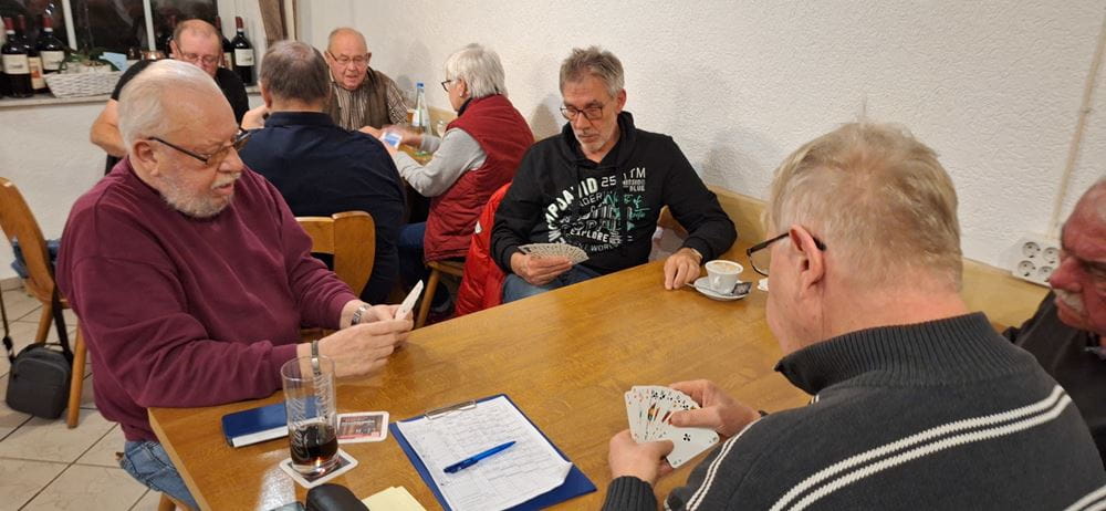An einem Tisch sieht man drei Männer mit Spielkarten in der Hand (Quelle: privat)