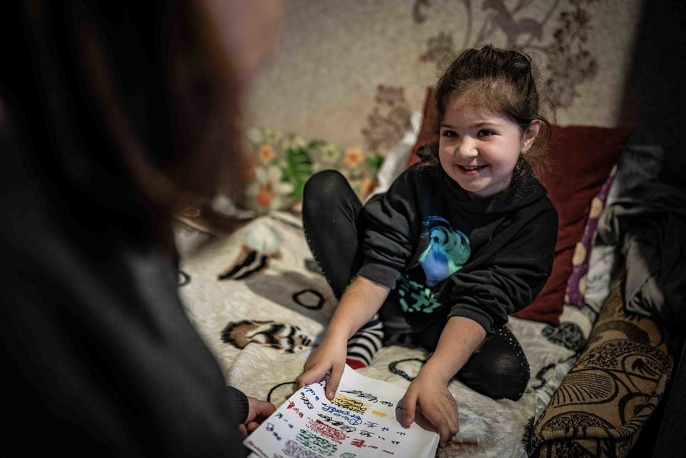 Mädchen sitzt aus dem Bett und zeigt selbst gemalte Bilder (Foto : Jakob Studnar / Kindernothilfe) Mädchen sitzt aus dem Bett und zeigt selbst gemalte Bilder (Foto : Jakob Studnar / Kindernothilfe)