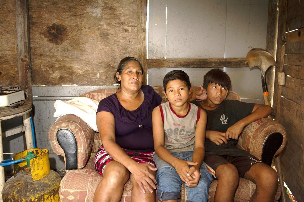 Eine Frau sitzt mit zwei Jungen auf einem Sofa in einer Hütte (Quelle: Christian Nusch)
