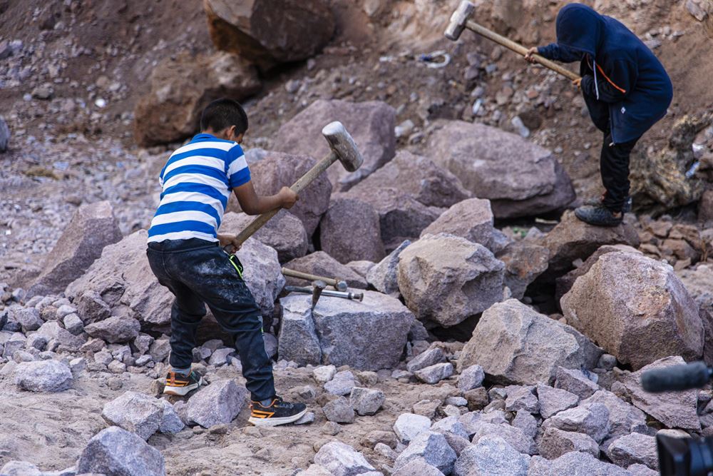 Ein Junge schwingt einen Vorschlaghammer in einem Steinbruch (Quelle: Martin Bondzio)