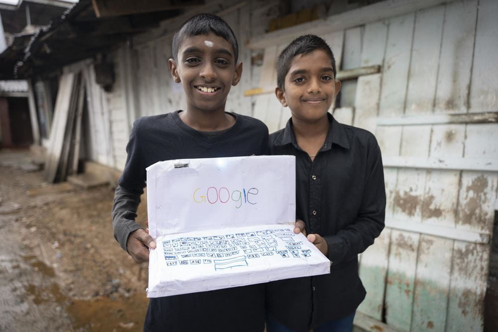 Zwei Jungen zeigen einen aus Papier gebastelten Laptop (Quelle: Christian Nusch)