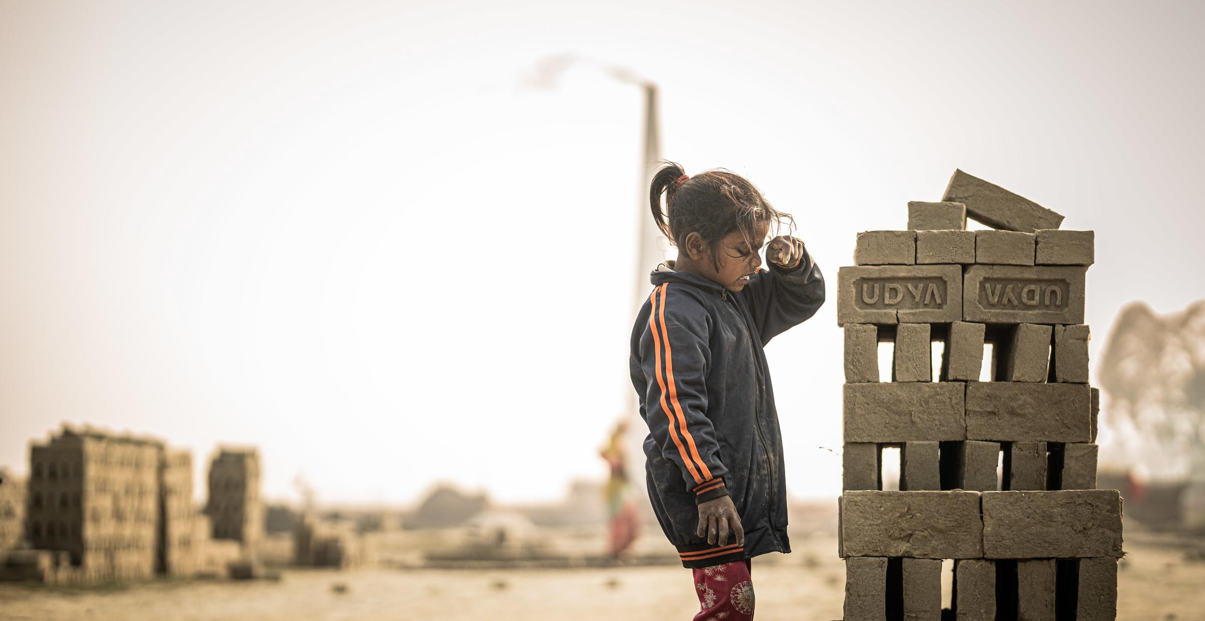 Eine Mädchen in einer Ziegelei in Nepal verschnauft an einem Ziegelstapel (Quelle: Jakob Studnar)