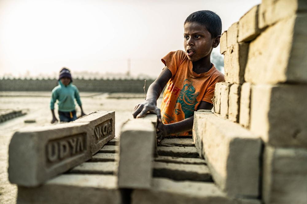 Junge in der Ziegelei stapelt Ziegel Foto : Jakob Studnar / Kindernothilfe. Platzhalterbild