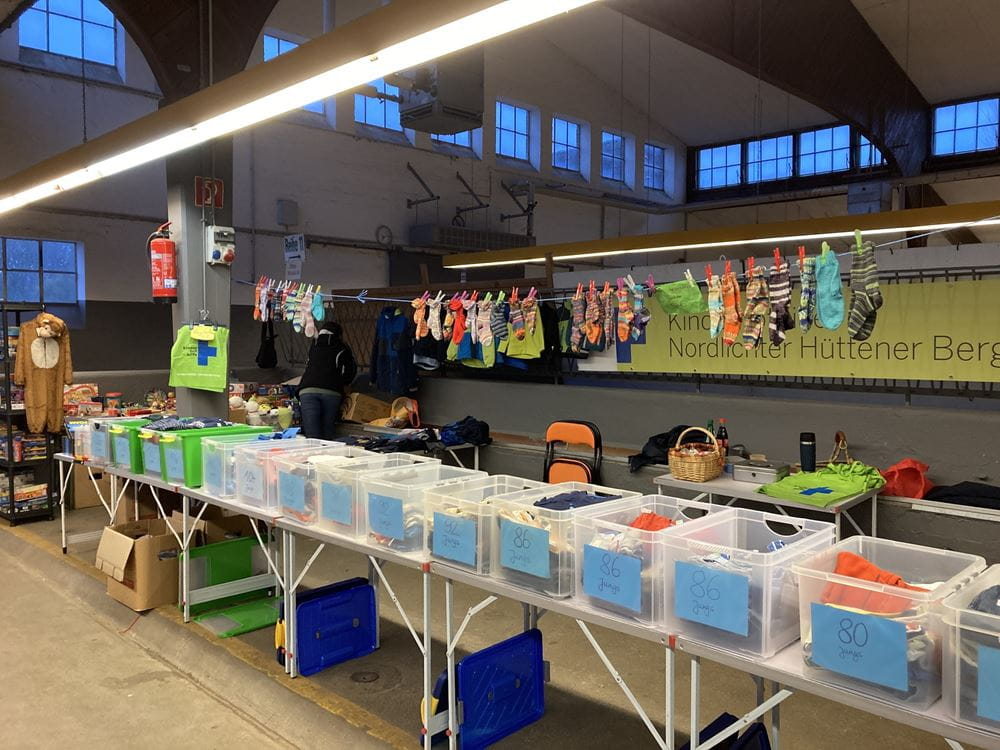 Eine lange Reihe von Tischen mit Babykleidung in einer Halle (Quelle: privat) Eine lange Reihe von Tischen mit Babykleidung in einer Halle (Quelle: privat)