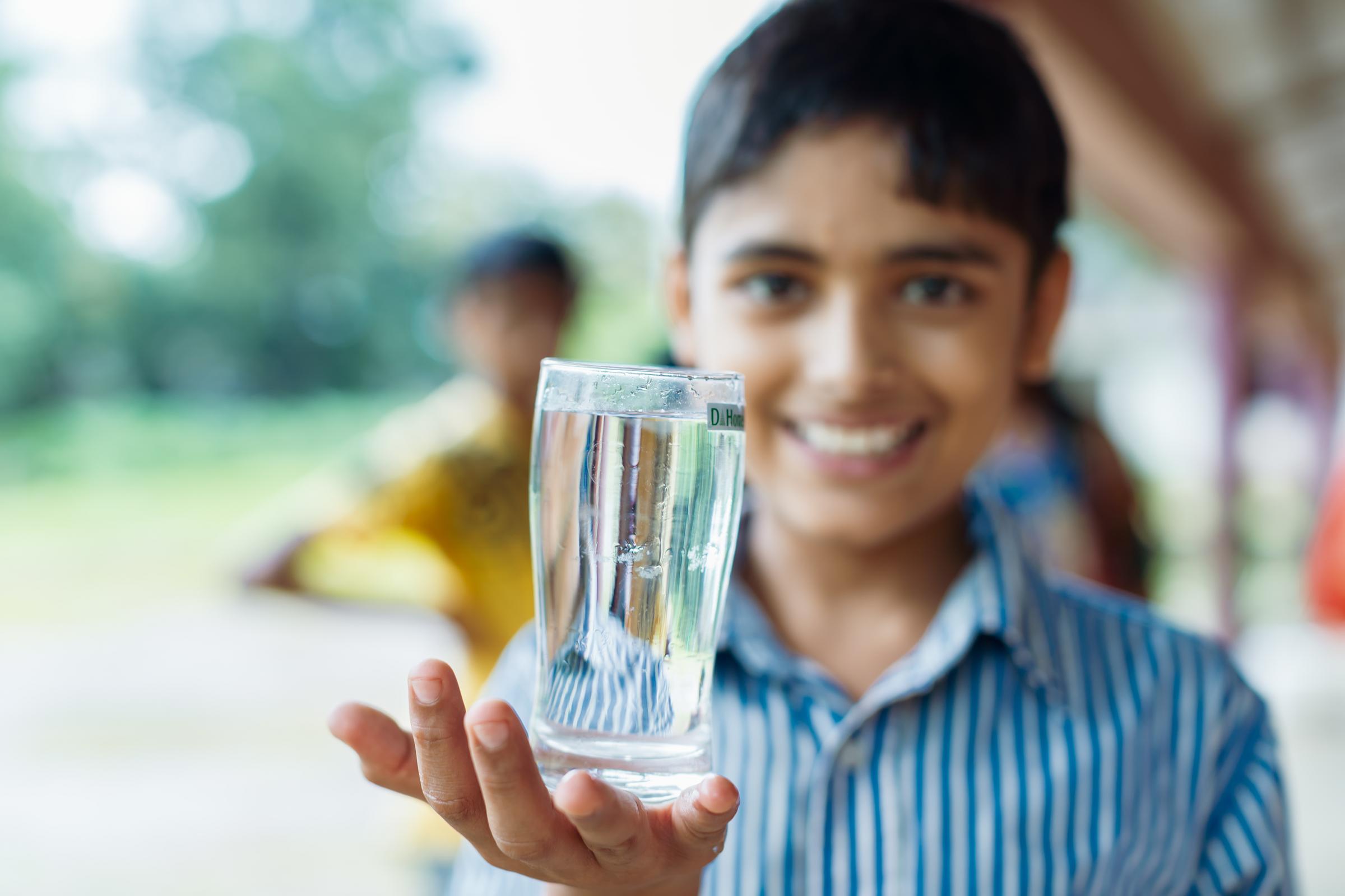 Ein Junge aus Indien hält ein Wasserglas in seiner Hand (Foto: Kindernothilfe / Jakob Studnar)
