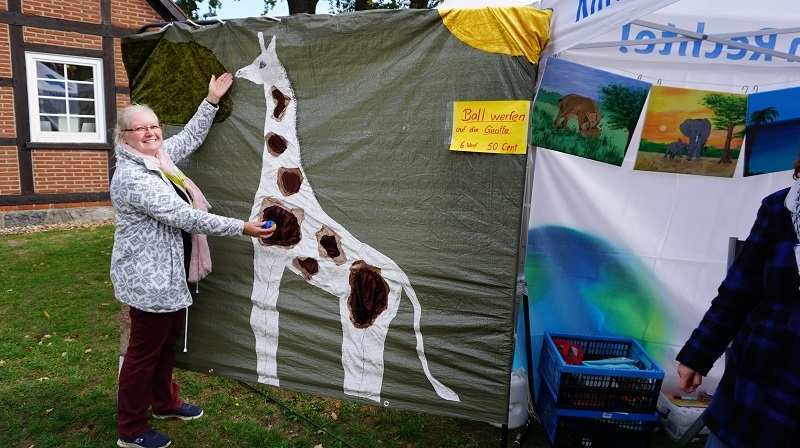 Eine Frau steht vor einer großen Tuchwand, auf die eine Giraffe genäht worden ist (Quelle: Ralf Krämer)