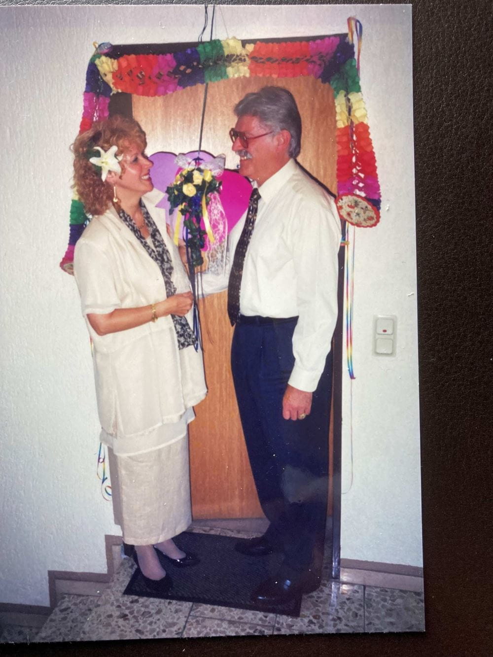 Ilka und Peter Flesch posieren vor einer geschmückten Tür anlässlich ihrer Hochzeit (Quelle: privat)