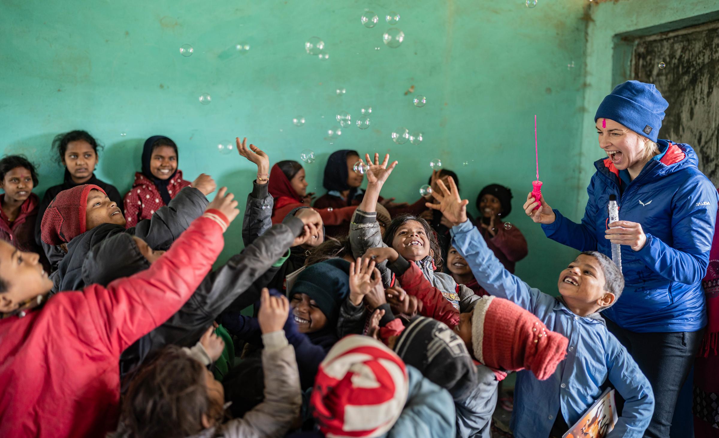 Sabine Heinrich und Kinder mit Seifenblasen in einem Klassenzimmer (Quelle: Jakob Studnar /  Kindernothilfe) Sabine Heinrich und Kinder mit Seifenblasen in einem Klassenzimmer (Quelle: Jakob Studnar /  Kindernothilfe)