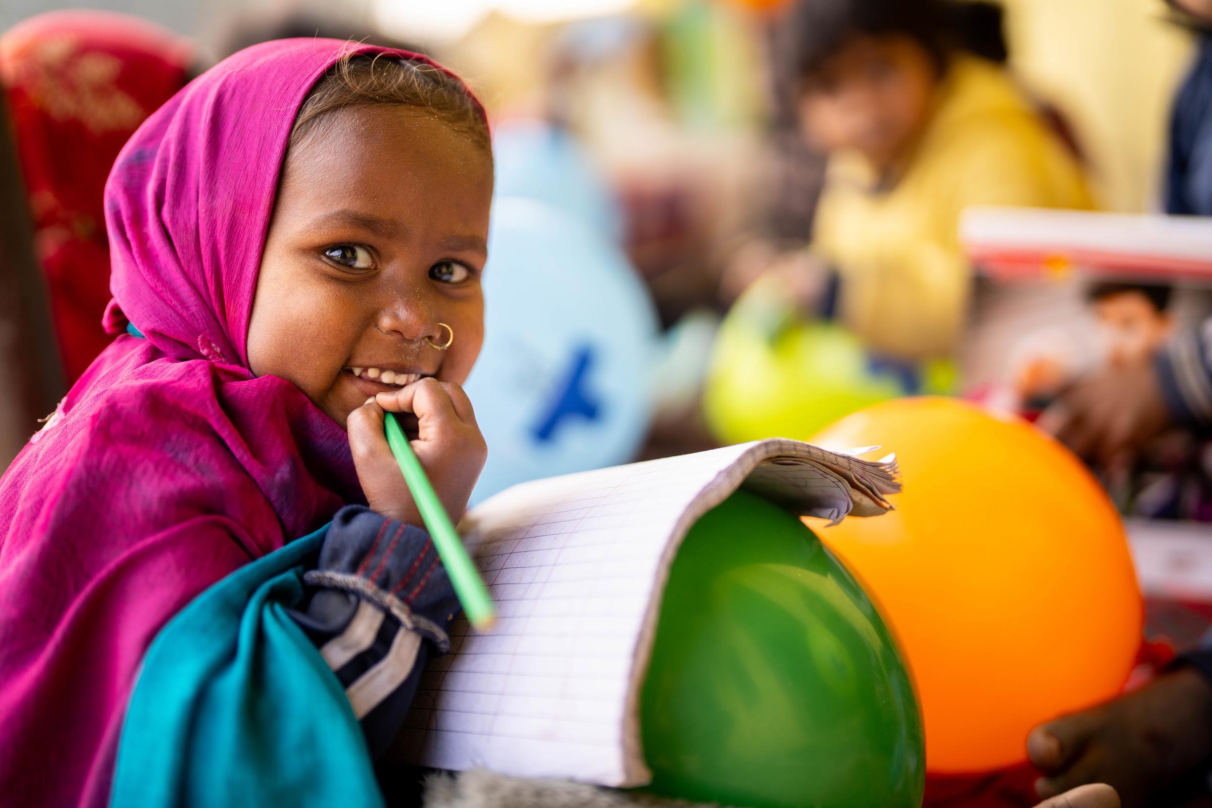 Ein kleines Mädchen aus Nepal hält einen Stift und einen Luftballon. (Quelle: Jakob Studnar)