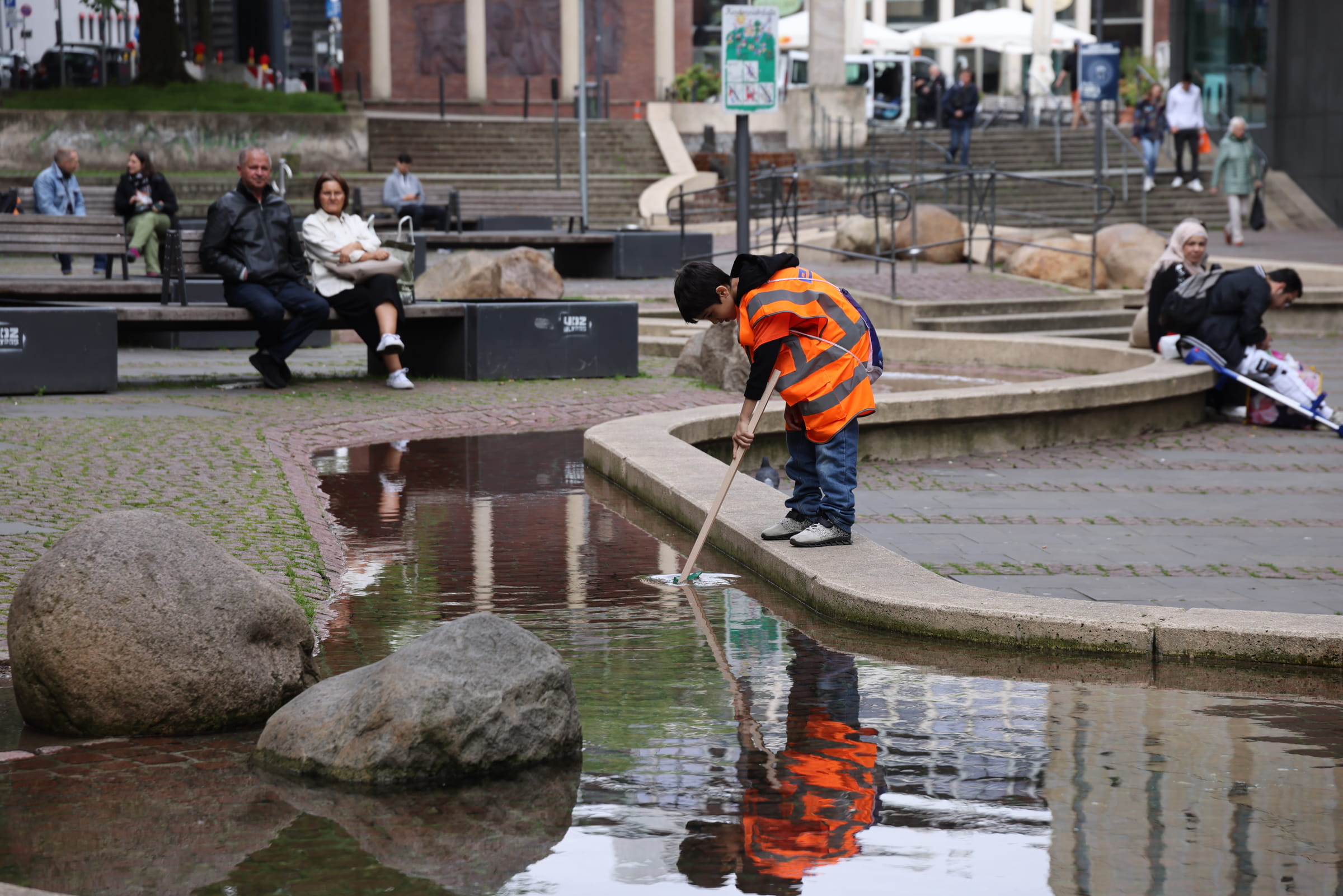 Junge in Warnweste fischt Müll aus dem Wasser (Ludwig Grunewald)
