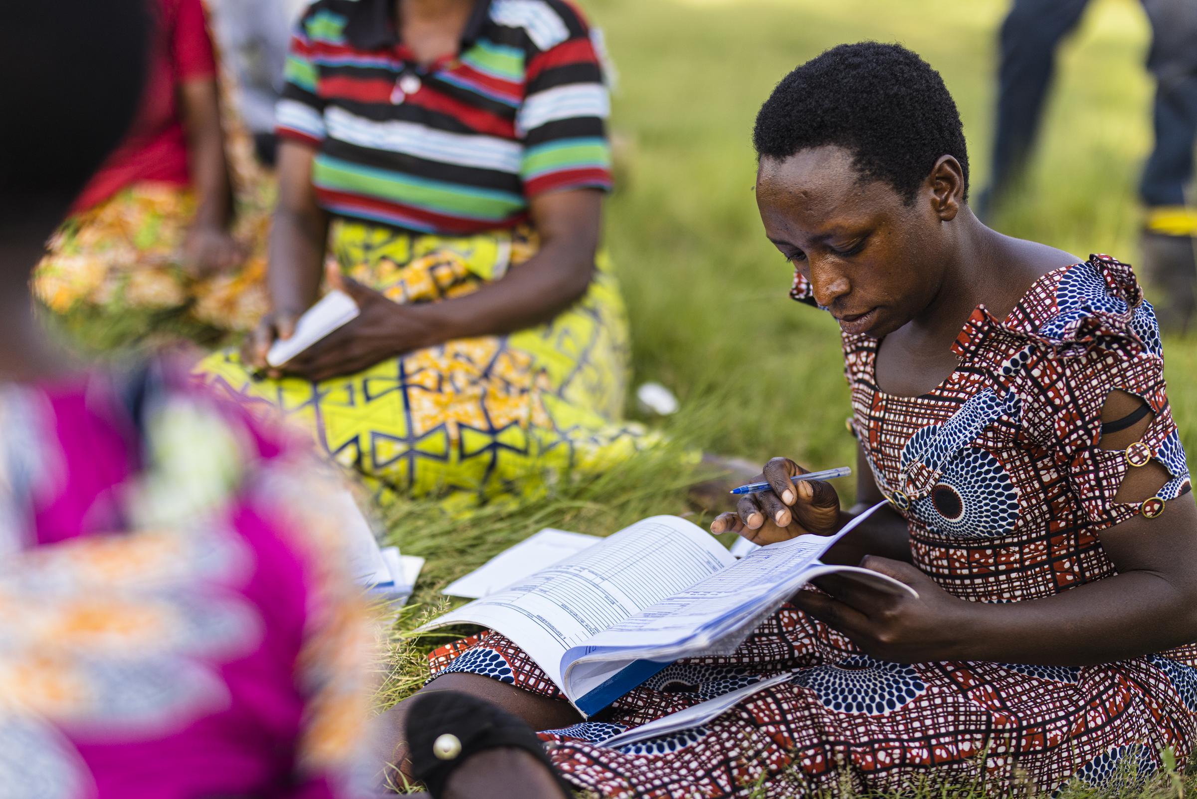 Eine Frau sitzt mit einem Heft in der Hand und liest darin (Quelle: Kindernothilfe)