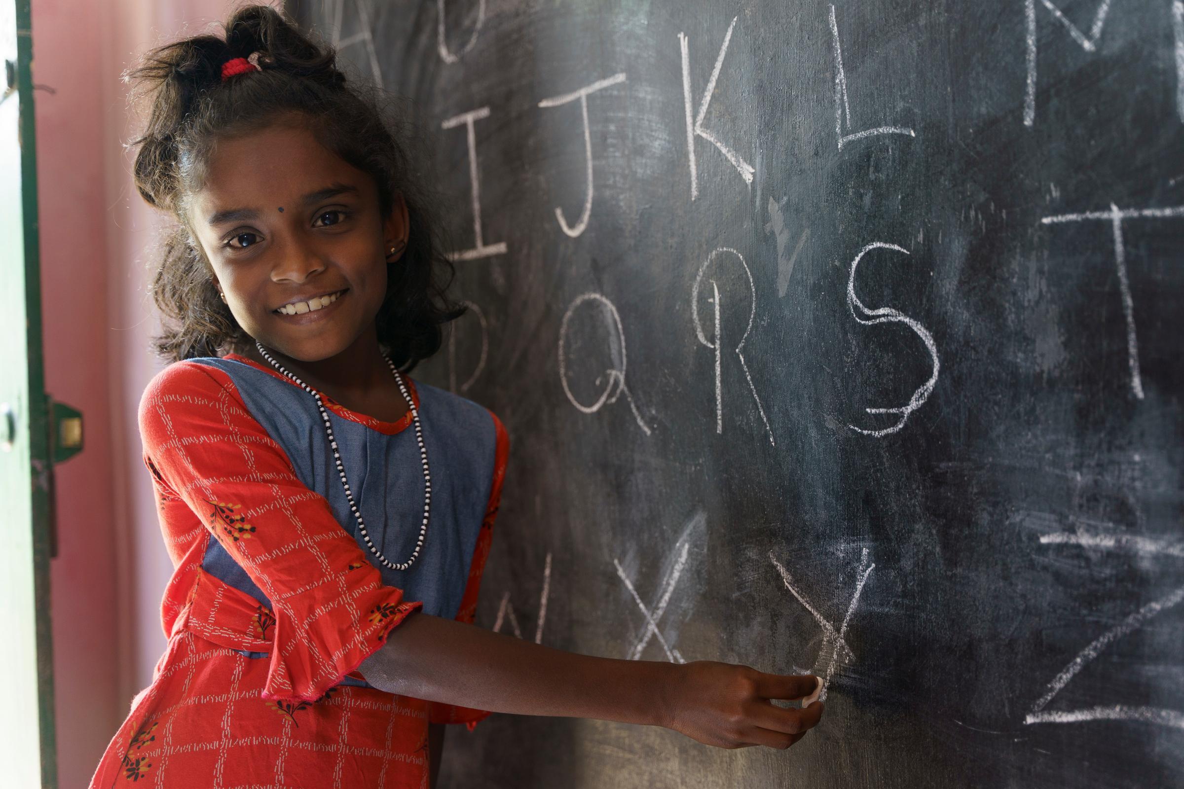 Ein Mädchen steht lachend an einer Tafel (Quelle: Christian Nusch)