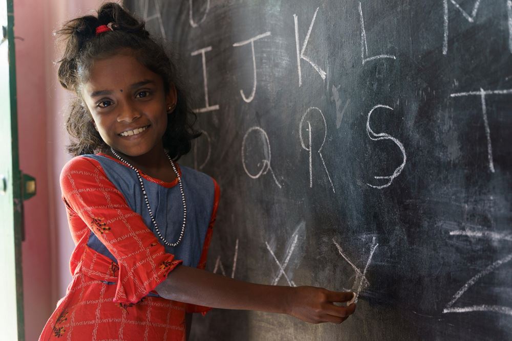 Ein Mädchen steht lachend an einer Tafel (Quelle: Christian Nusch) Ein Mädchen steht lachend an einer Tafel (Quelle: Christian Nusch)