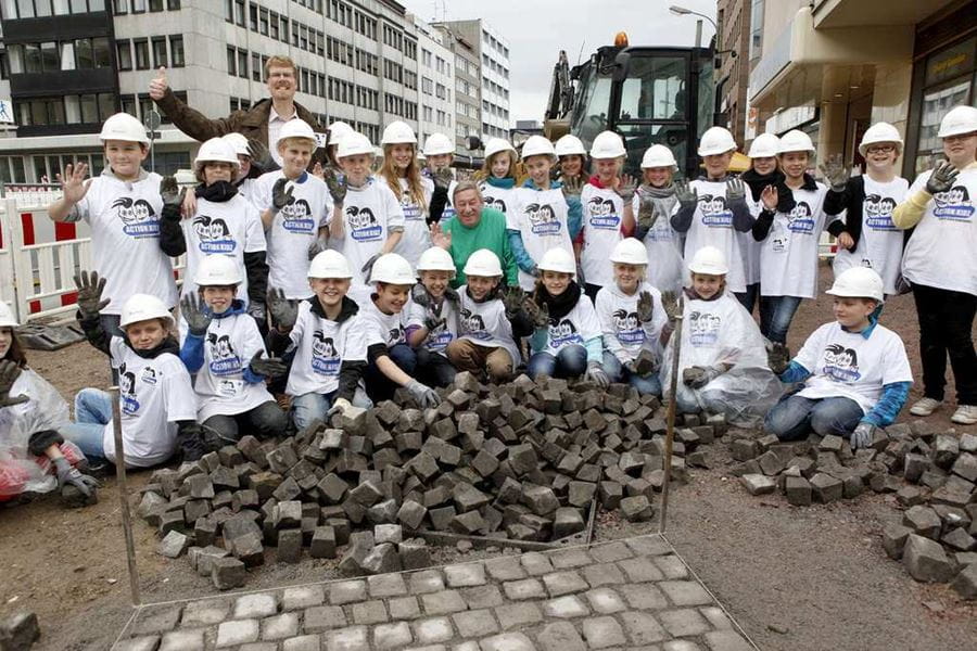 Christian Biemann mit einer großen ActionKidz Gruppe auf der Straße (Quelle: Kindernothilfe) Christoph Biemann lacht vor einem Kindernothilfebanner in die Kamera