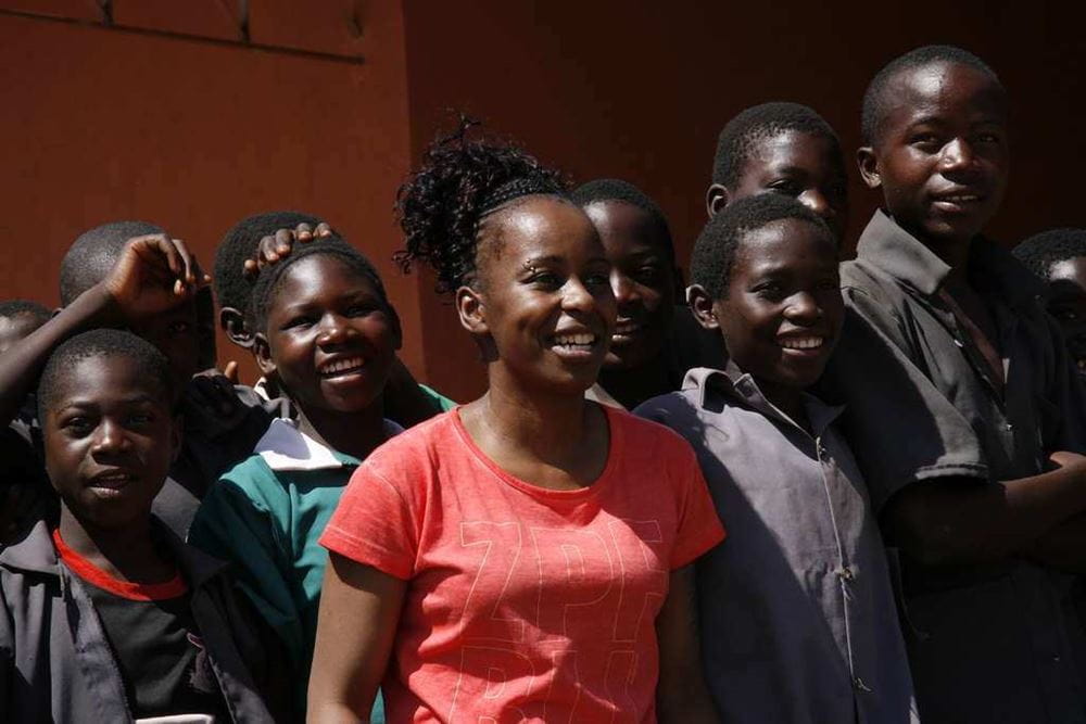 Shary Reeves auf Projektbesuch in Sambia steht zwischen Jugendlichen (Quelle: Kindernothilfe) Shary Reeves besucht ein Projekt der Kindernothilfe in Sambia und sitzt im Aufnahmestudio, das das Programm des Schulradios sendet