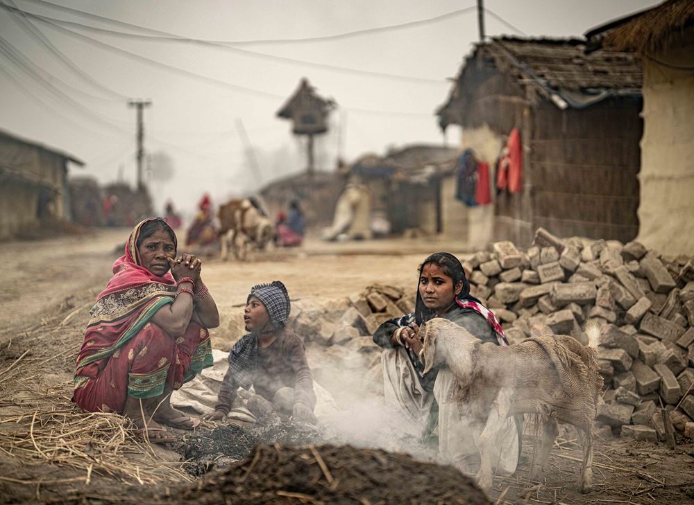 Eine Familie sitzt um ein Feuer auf der Straße, ihre Ziege trägt einen Jutesack über dem Rücken (Quelle: Jakob Studnar) Eine Familie sitzt um ein Feuer auf der Straße, ihre Ziege trägt einen Jutesack über dem Rücken (Quelle: Jakob Studnar)