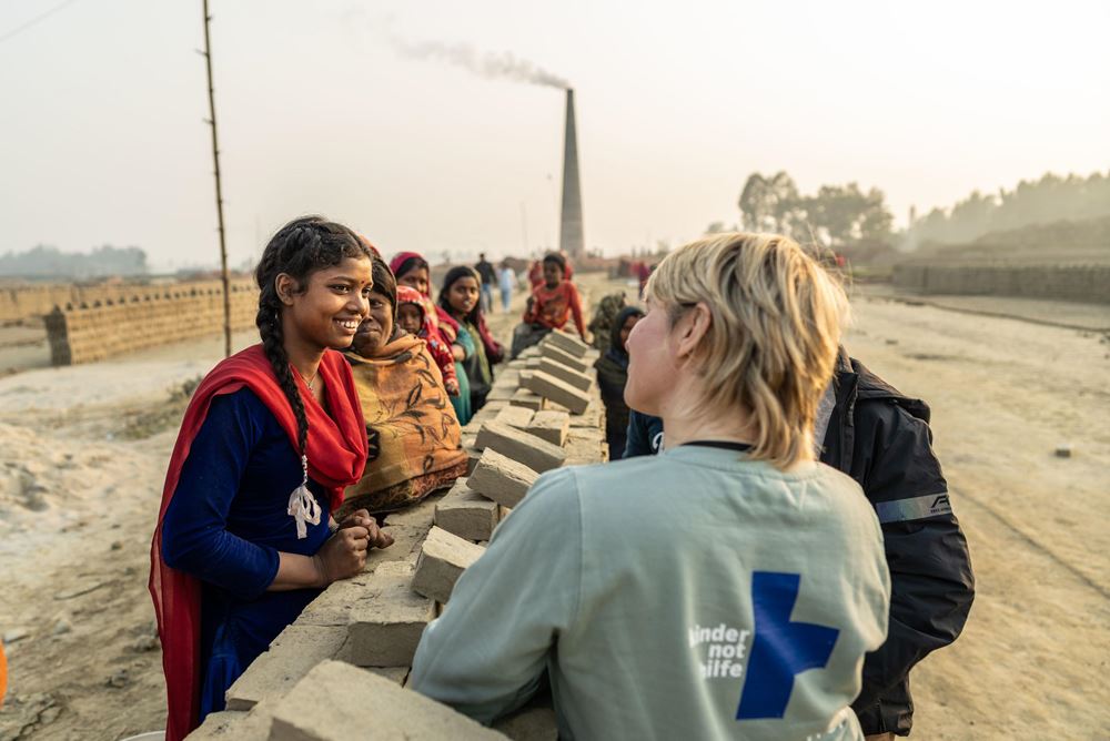 Sabine Heinrich steht an einer Mauer aus aufeinandergestapelten Ziegeln und unterhält sich mit einem Mädchen mit langen Zöpfen (Quelle: Jakob Studnar) Sabine Heinrich steht an einer Mauer aus aufeinandergestapelten Ziegeln und unterhält sich mit einem Mädchen mit langen Zöpfen (Quelle: Jakob Studnar)