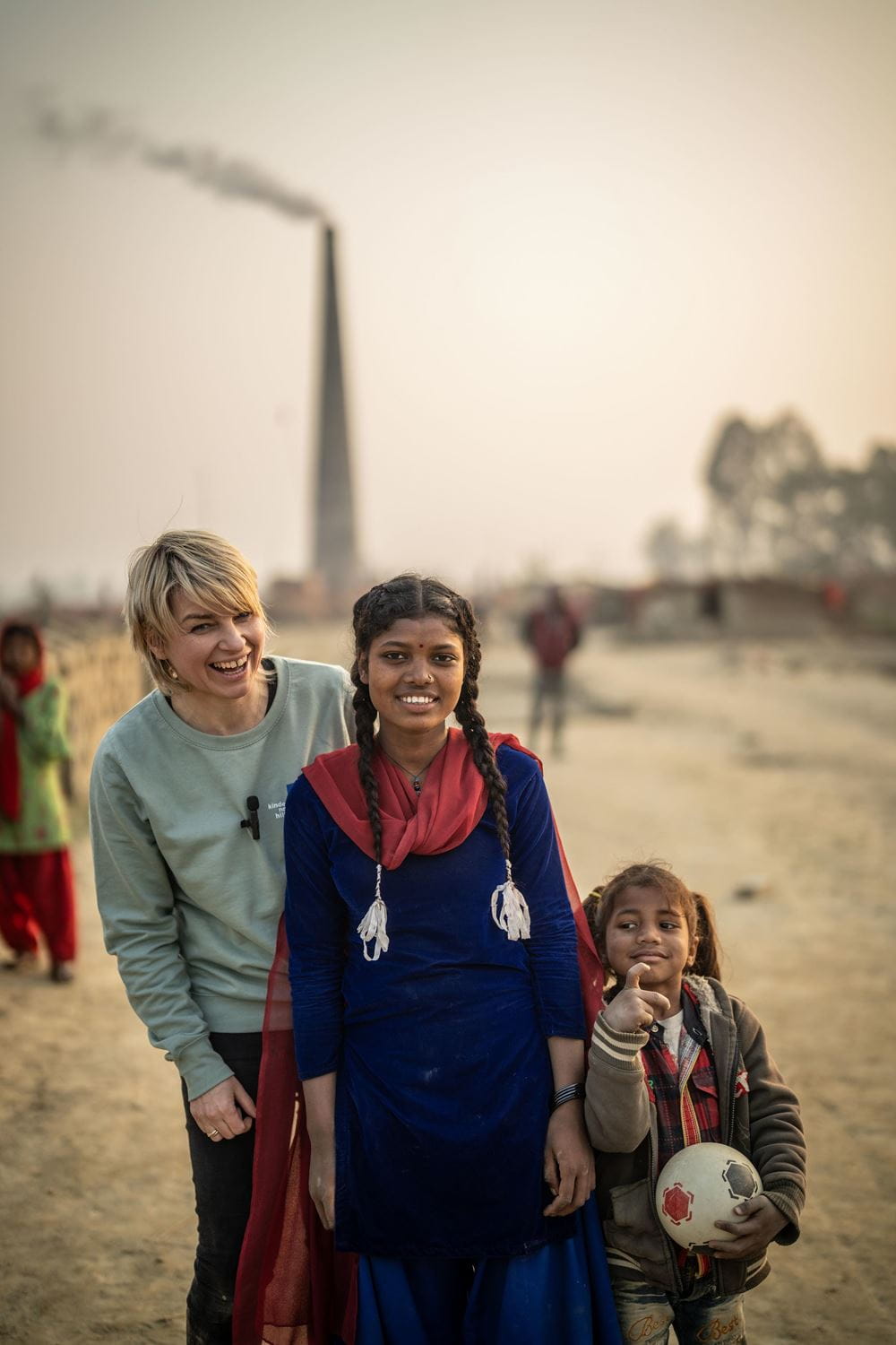 Sabine Heinrich steht mit einem Mädchen mit zwei langen Zöpfen, blauem Kleid und rotem Tuch vor dem Schornstein eines Ziegelei-Brennofens (Quelle: Jakob Studnar) Sabine Heinrich steht mit einem Mädchen mit zwei langen Zöpfen, blauem Kleid und rotem Tuch vor dem Schornstein eines Ziegelei-Brennofens (Quelle: Jakob Studnar)