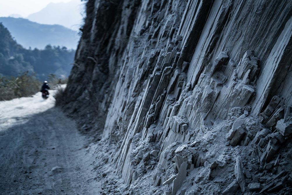 Ein steiler Berghang, an dem ein Motorrad auf einer unbefestigten Straße vorbeifährt (Quelle: Jakob Studnar) Ein steiler Berghang, an dem ein Motorrad auf einer unbefestigten Straße vorbeifährt (Quelle: Jakob Studnar)