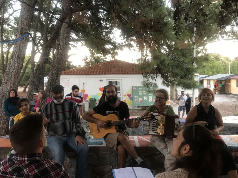 Menschen sitzen zusammen und musizieren (Quelle: Lesvos Solidarity) Menschen sitzen zusammen und musizieren (Quelle: Lesvos Solidarity)