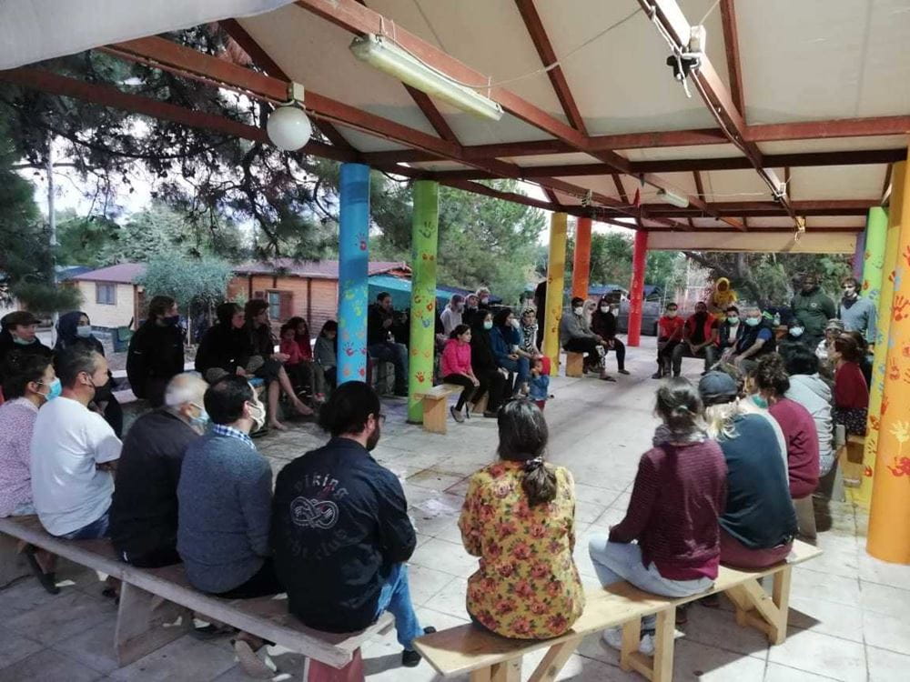 Menschen sitzen zusammen im Camp (Quelle: Lesvos Solidarity) Menschen sitzen zusammen im Camp (Quelle: Lesvos Solidarity)