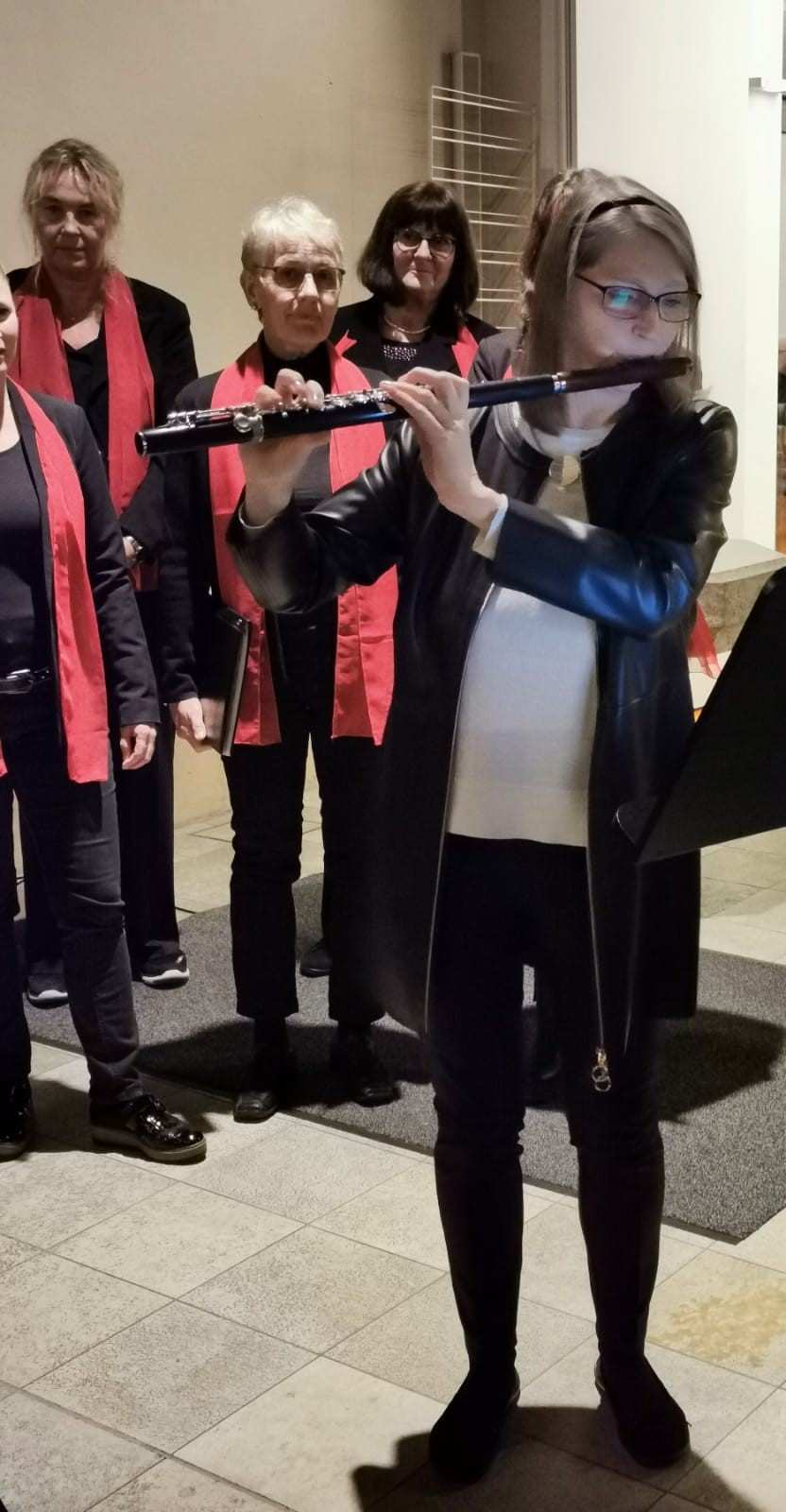 Eine junge Frau spielt Querflöte, hinter ihr stehen einige Mitglieder des Frauenchors (Quelle: privat) Eine junge Frau spielt Querflöte, hinter ihr stehen einige Mitglieder des Frauenchors (Quelle: privat)