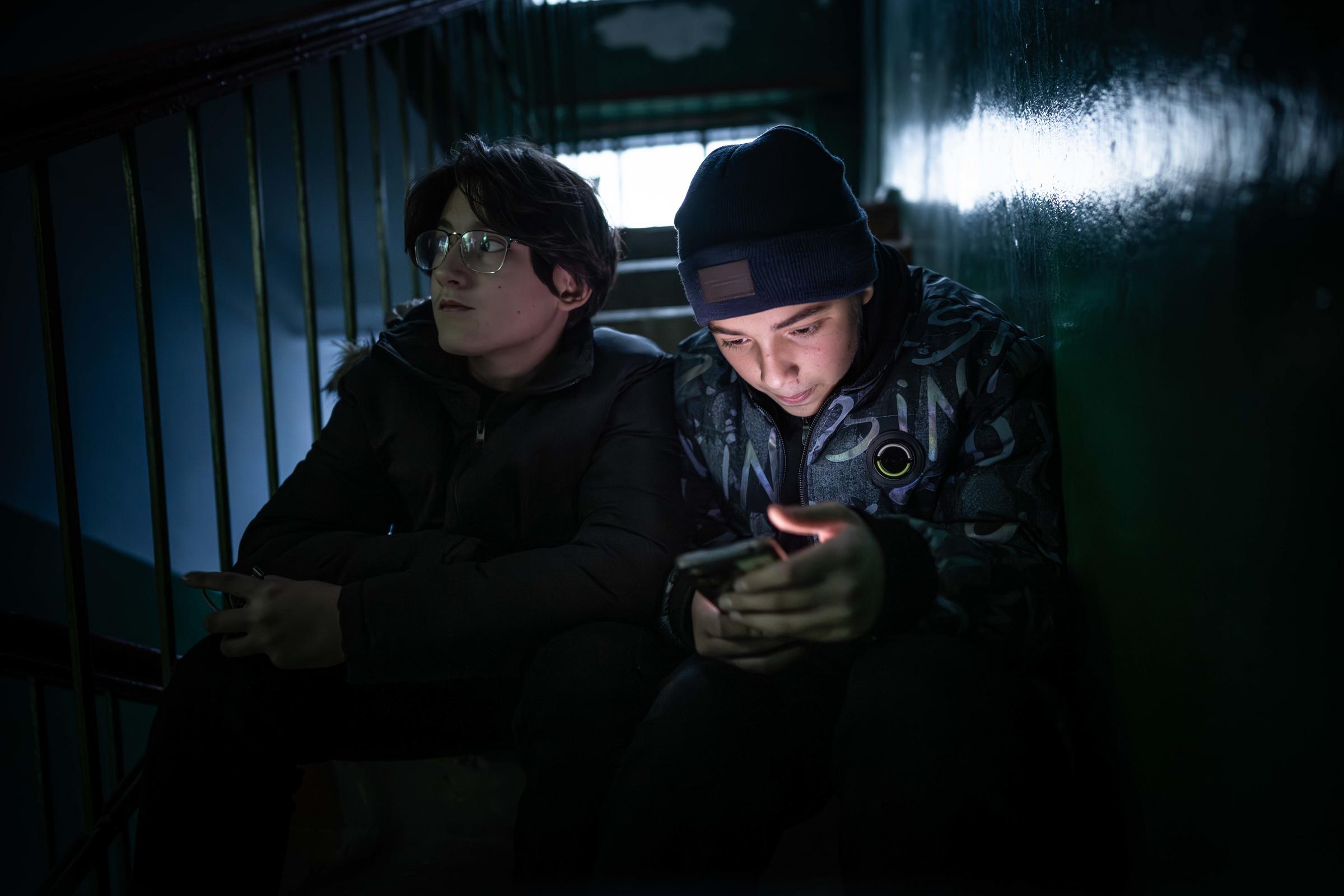 Zwei Jugendliche mit Smartphones auf einer Treppe im Hausflur (Quelle: Jakob Studnar / Kindernothilfe)