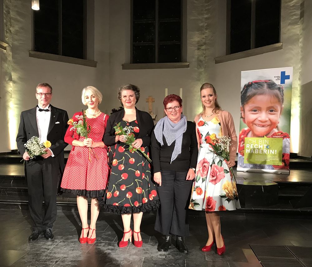 Ein Mann und drei Frauen mit Blumensträußen sowie eine weitere Frau stehen vor einem Kindernothilfe-Poster in einer Kirche (Quelle: privat) Ein Mann und drei Frauen mit Blumensträußen sowie eine weitere Frau stehen vor einem Kindernothilfe-Poster in einer Kirche (Quelle: privat)