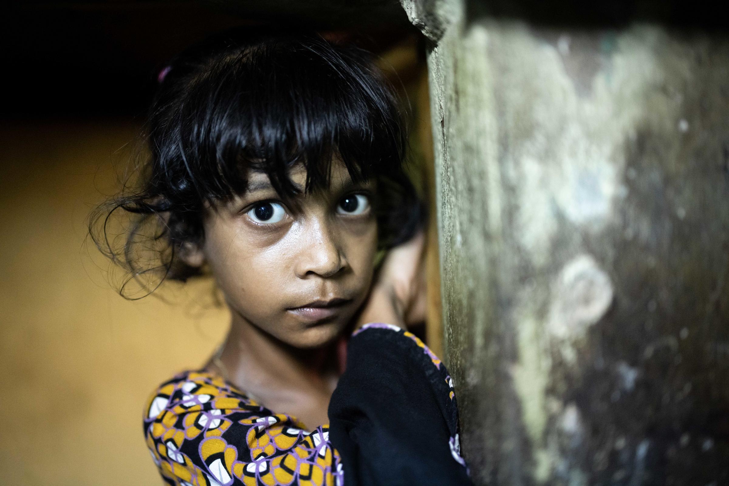 Ein Mädchen aus Bangladesch schaut schüchtern um die Ecke. (Quelle: Lars Heidrich)