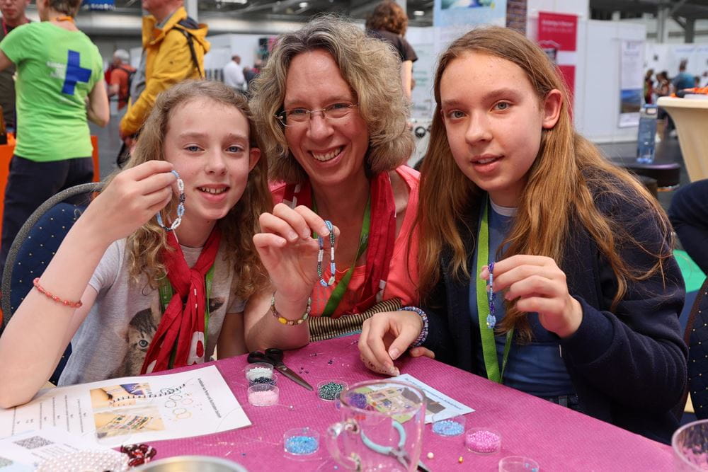 Beim Markt der Möglichkeiten am Kirchentag basteln Familien Armbänder (Foto: Katharina Draub/Kindernothilfe) Beim Markt der Möglichkeiten am Kirchentag basteln Familien Armbänder (Foto: Katharina Draub/Kindernothilfe)