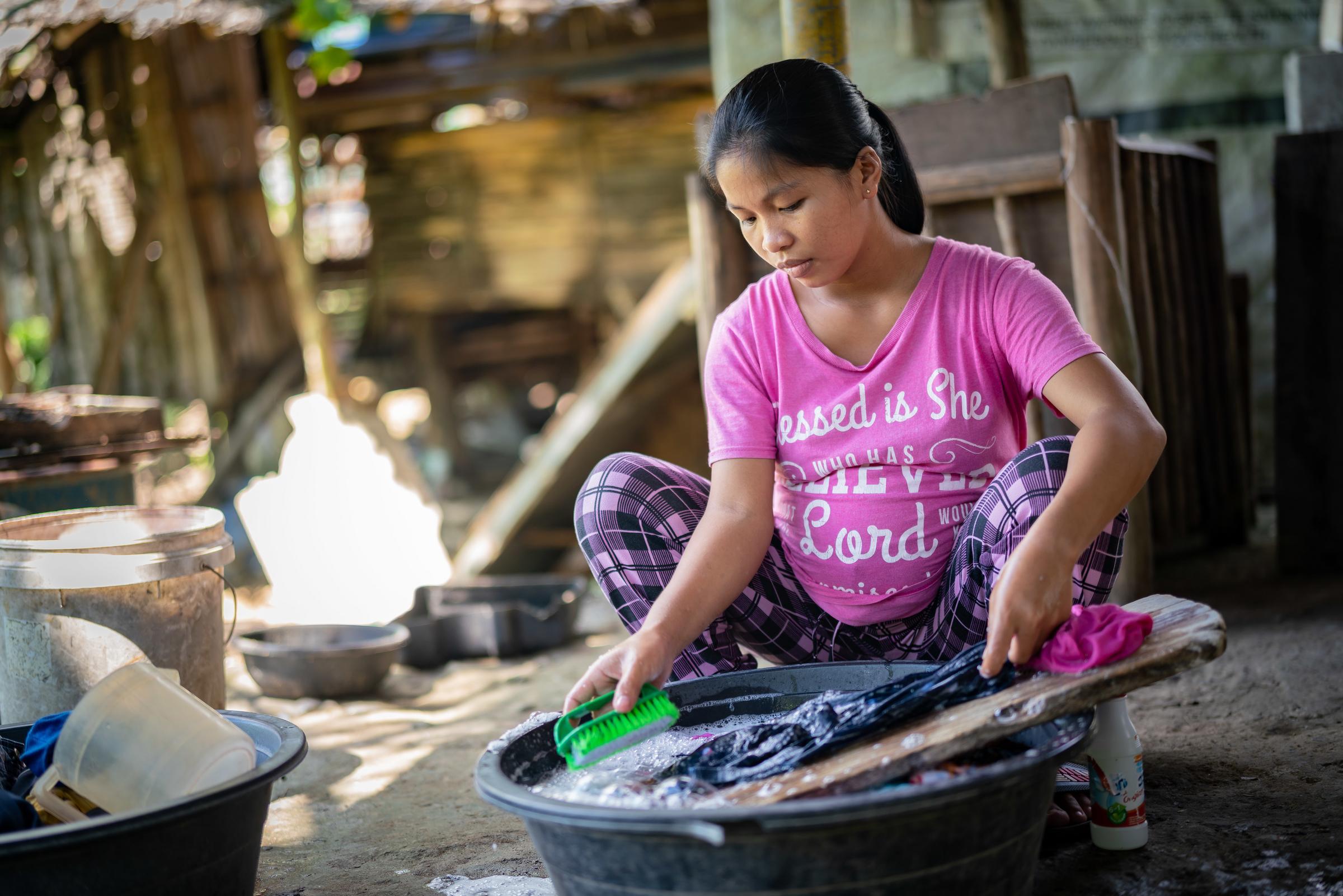 Die schwangere Rose hockt auf dem Boden und wäscht Kleidung (Quelle: Jakob Studnar)