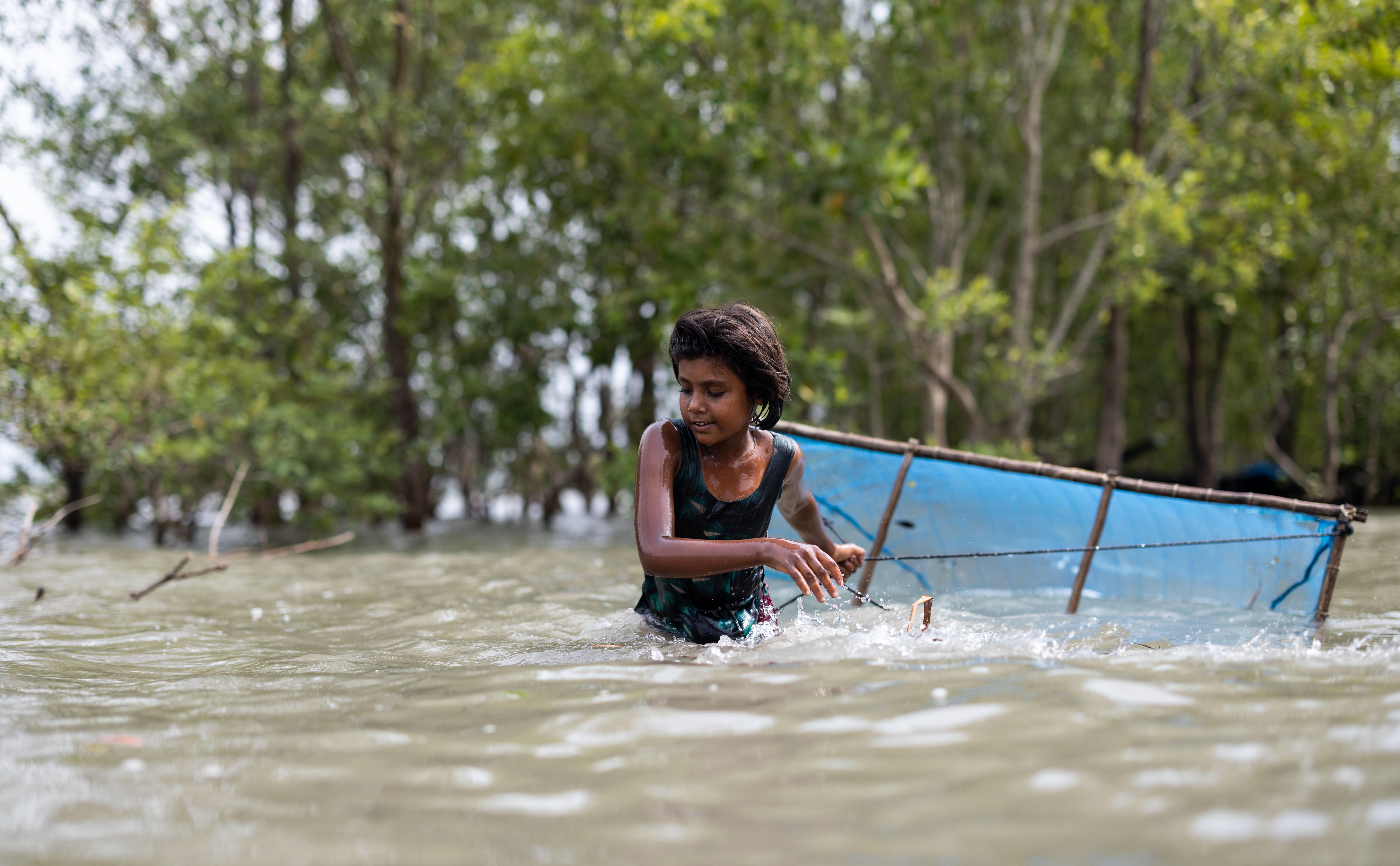 Ein Mädchen in Bangladesch watet mit einem Netz durchs Wasser. (Quelle: Lars Heidrich) 