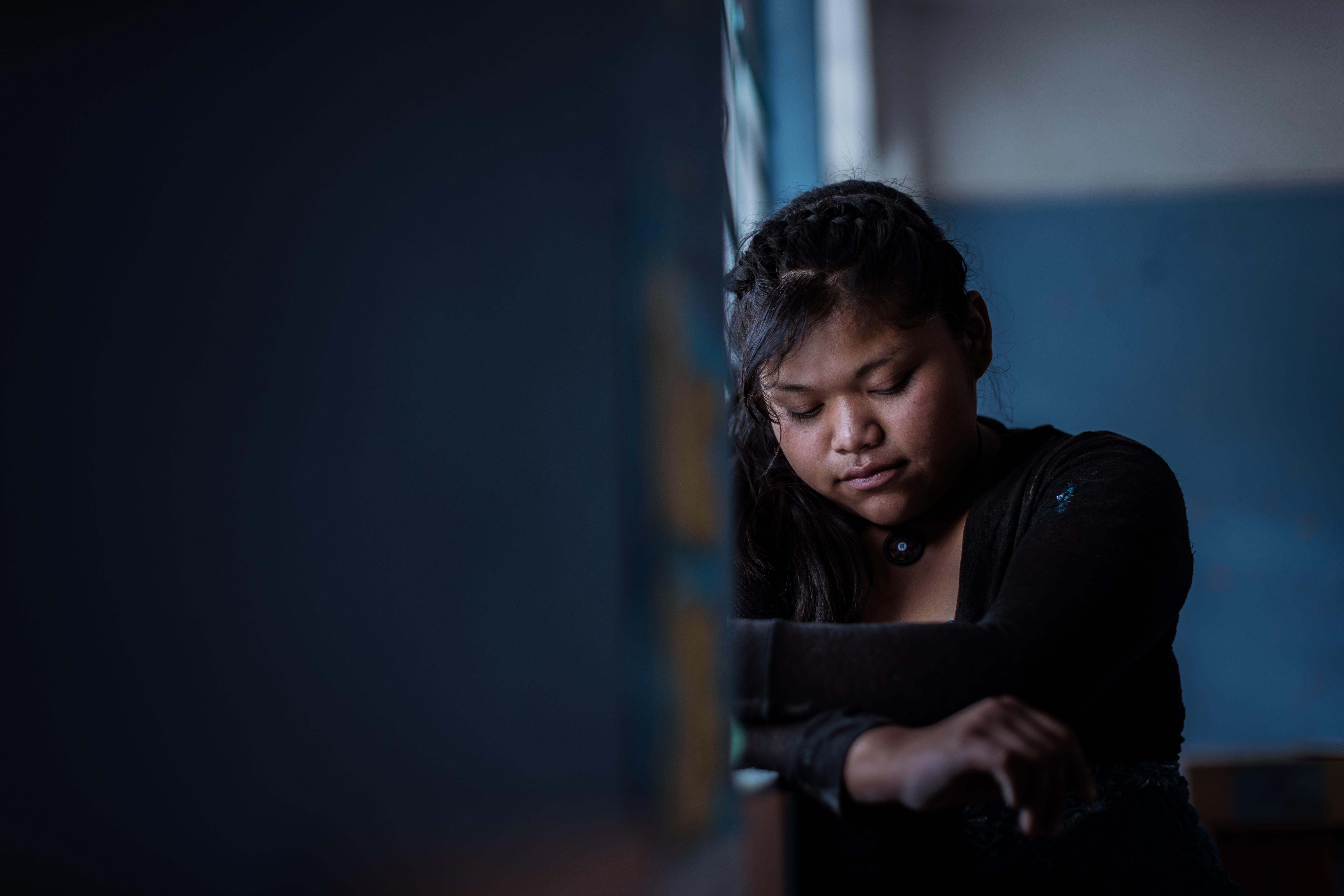 Ein Mädchen steht am Fenster und blickt traurig zu Boden (Quelle: Jakob Studnar)