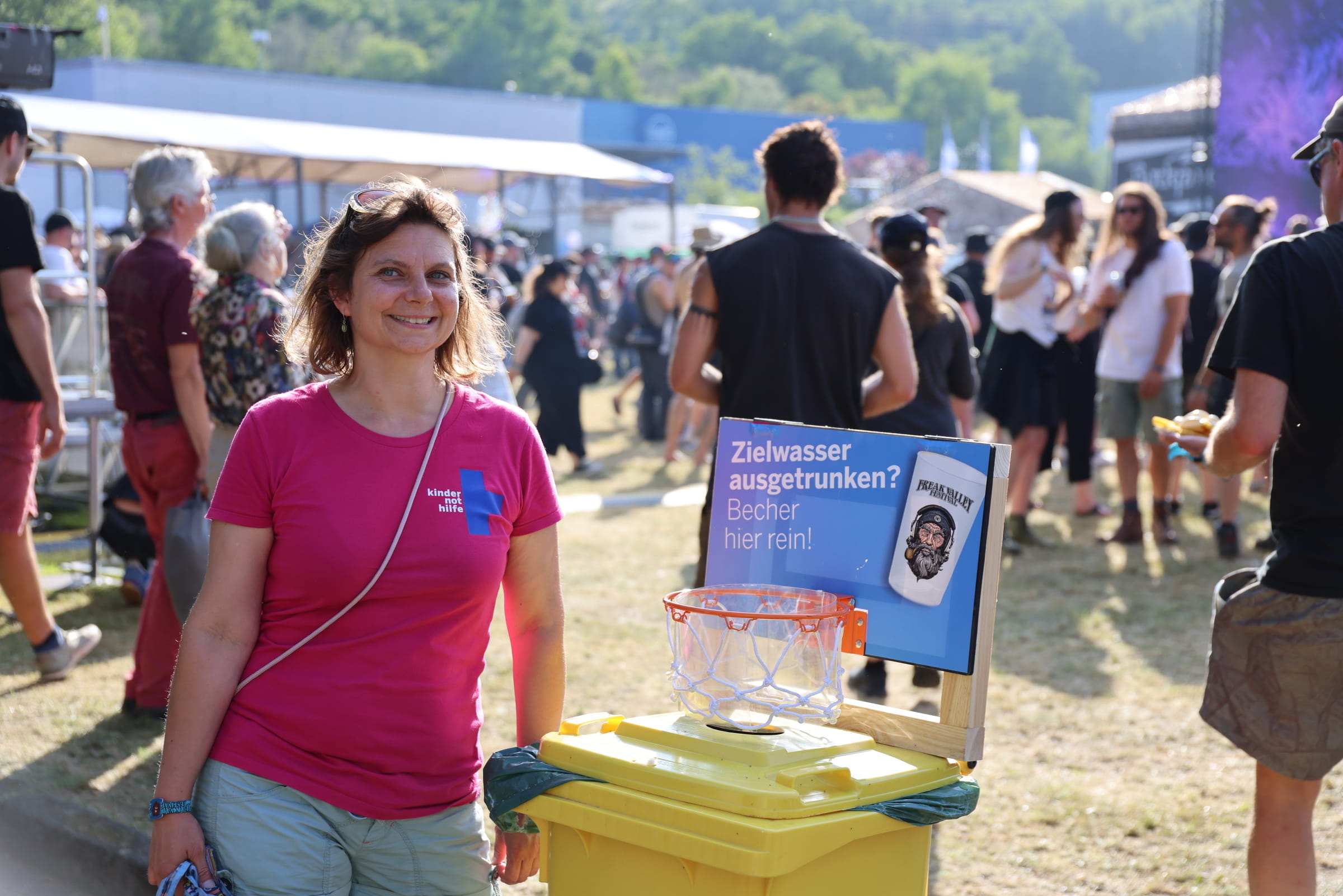 Eine Ehrenamtliche neben einer Pfandbechertonne auf dem Freak-Valley-Festival 2025 in Netphen (Quelle: Kindernothilfe)