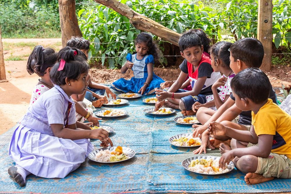 Kinder aus Sri Lanka sitzen gemeinsam auf einer Decke auf dem Boden und essen (Quelle: Sharni Jayawardena/Kindernothilfe) Kinder aus Sri Lanka sitzen gemeinsam auf einer Decke auf dem Boden und essen (Quelle: Sharni Jayawardena/Kindernothilfe)