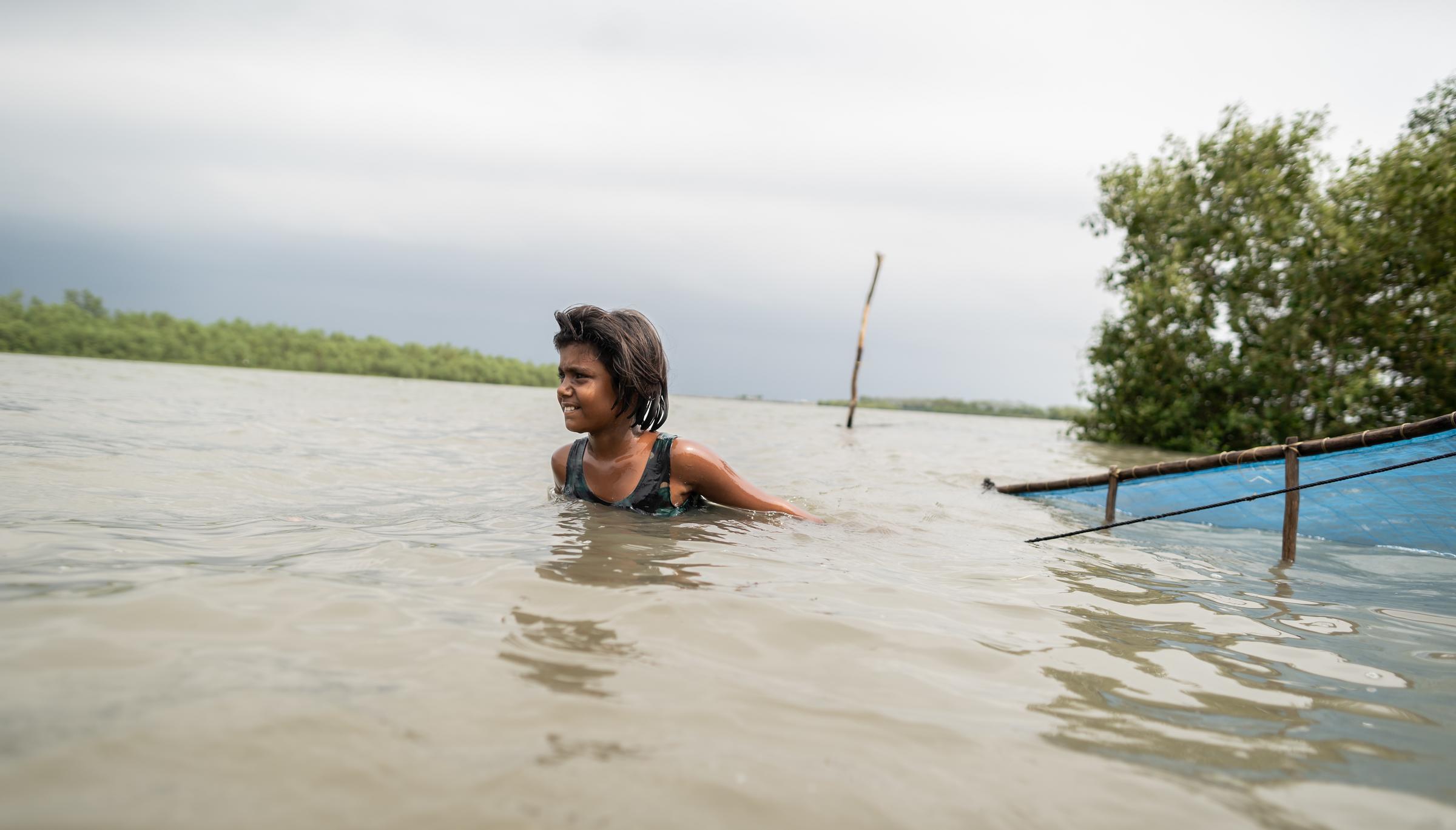 Mädchen in Bangladesch watet durch Wasser, das ihr bis zum Hals steht