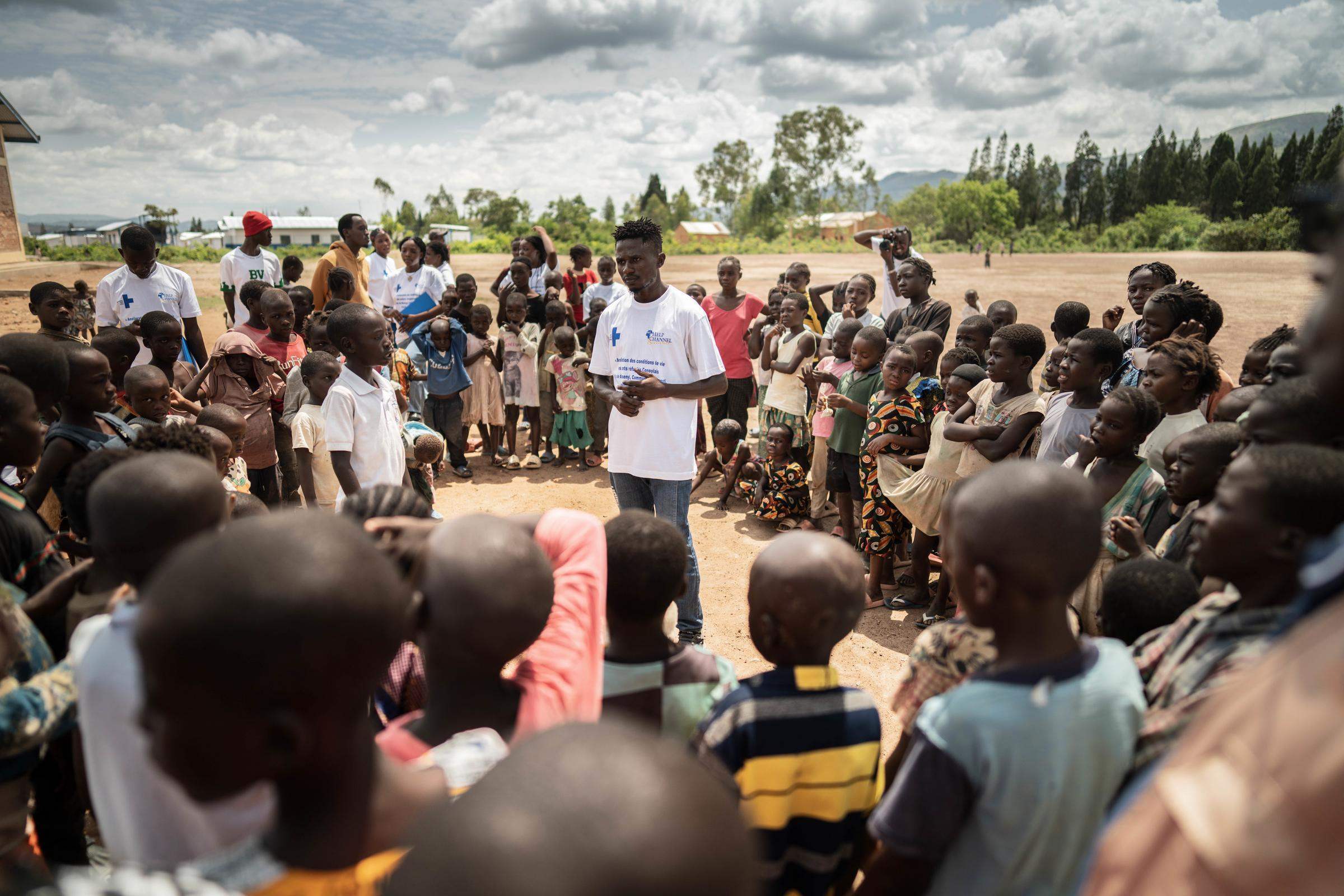  Jugendclub des Musenyi Camps: Kinder und Jugendliche stehen im Kreis um den Mitarbeiter des Kindernothilfe-Partners 