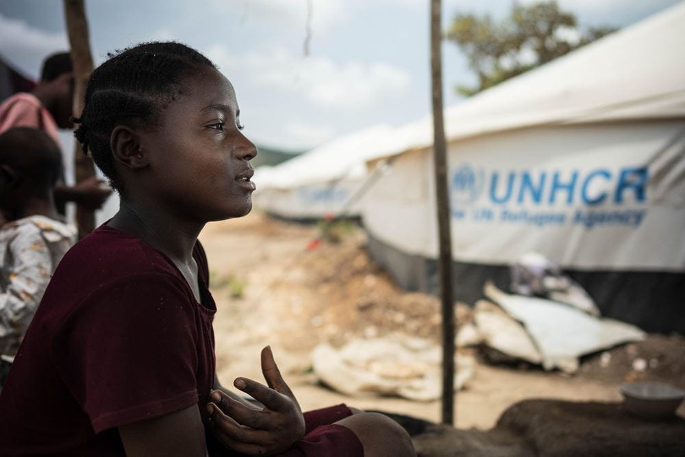 Bahati sitzt im Schatten, im Hintergrund sieht man ein Zelt (Quelle: Jakob Studnar) Bahati sitzt im Schatten, im Hintergrund sieht man ein Zelt (Quelle: Jakob Studnar)