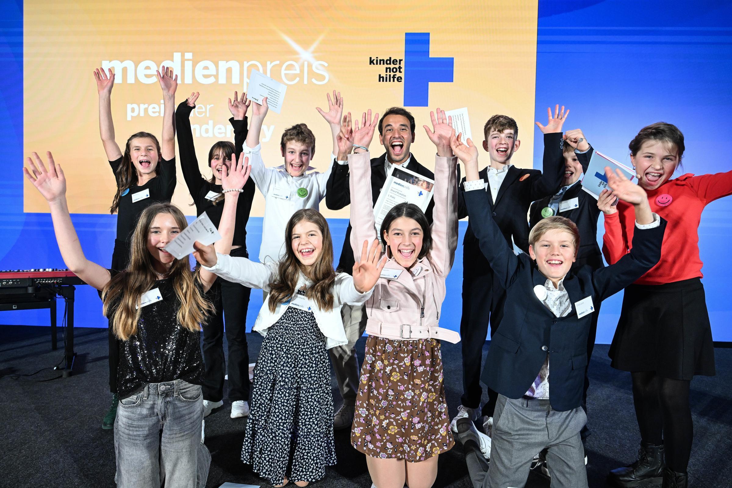 Sherif Rizkallah mit der Kinderjury auf der Bühne bei der Kindernothilfe-Medienpreisverleihung 2025 (Quelle: Reto Klar) Sherif Rizkallah mit der Kinderjury auf der Bühne bei der Kindernothilfe-Medienpreisverleihung 2025 (Quelle: Reto Klar)