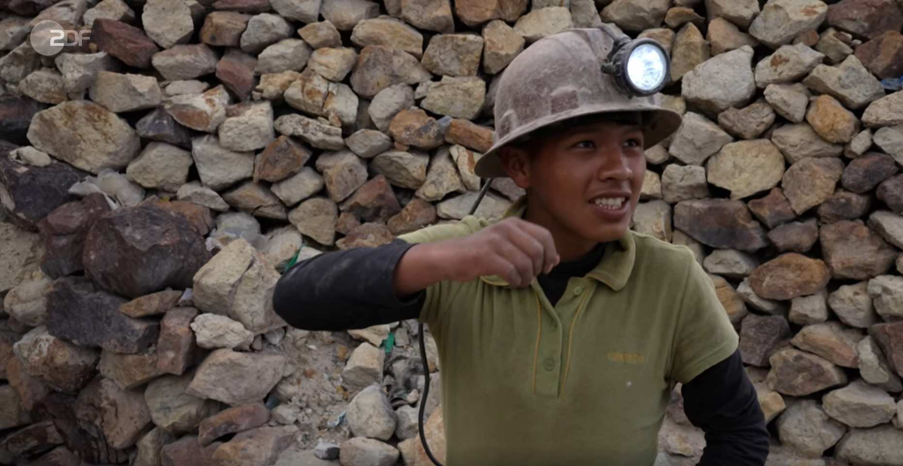 Kevin, ein 14-jähriger Junge aus Bolivien arbeitet in einer Mine. Er trägt staubige Kleidung und einen Bergbauhelm mit einer Lampe.
