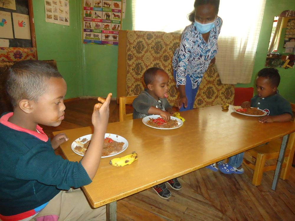 Kinder sitzen am Tisch und essen. (Quelle: Kindernothilfe-Partner) Platzhalterbild