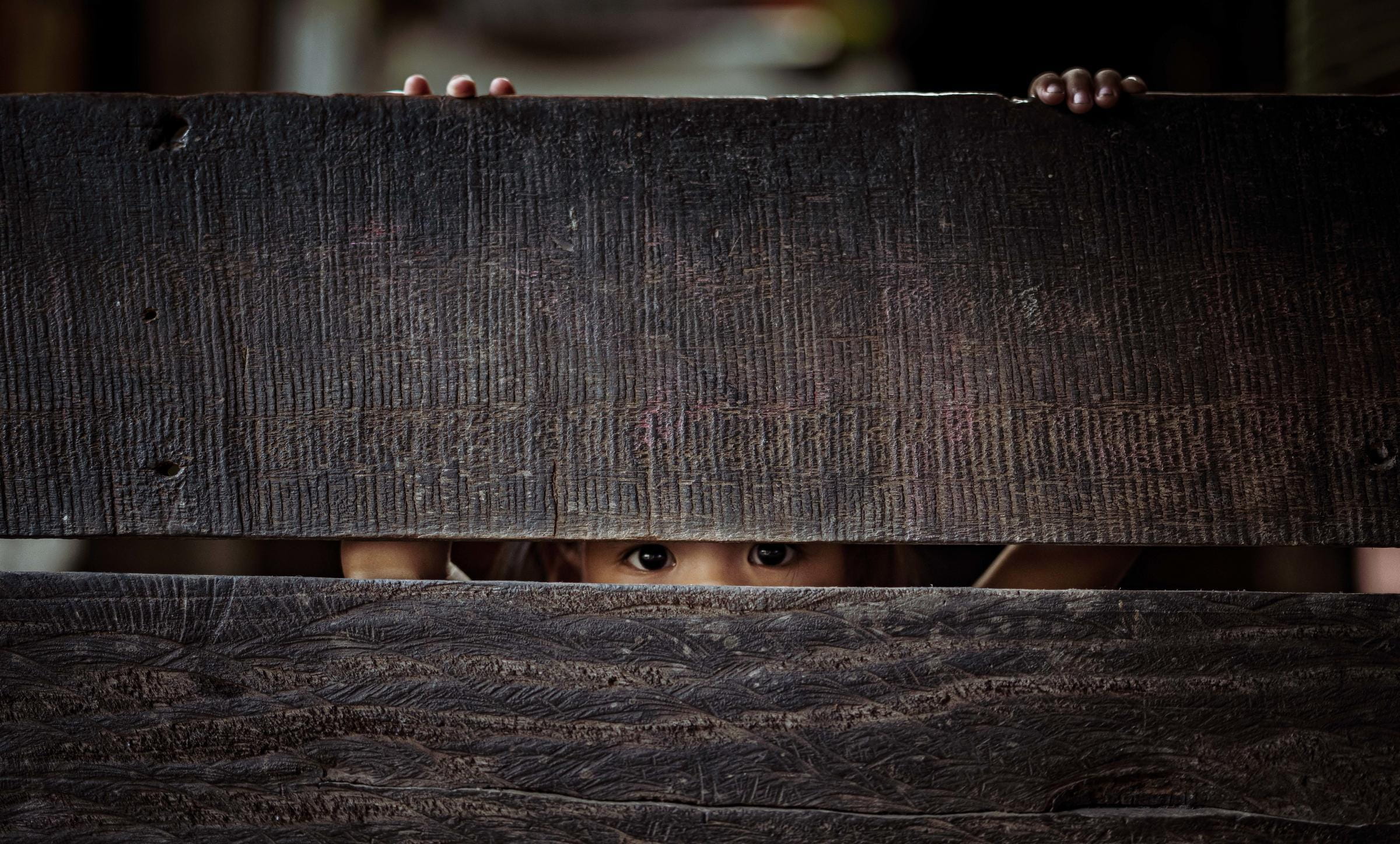 Ein Kind schaut durch einen Spalt; Foto: Jakob Studnar