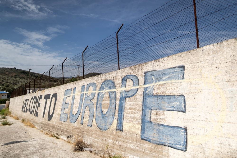 Symbolbild Flucht: Grenzmauer mit Stacheldraht an der europäischen Grenze auf Lesbos (Griechenland) mit der Graffiti-Aufschrift "Welcome to Europe" (Quelle: Lars Heidrich/Kindernothilfe) Symbolbild Flucht: Grenzmauer mit Stacheldraht an der europäischen Grenze auf Lesbos (Griechenland) mit der Graffiti-Aufschrift "Welcome to Europe" (Quelle: Lars Heidrich/Kindernothilfe)