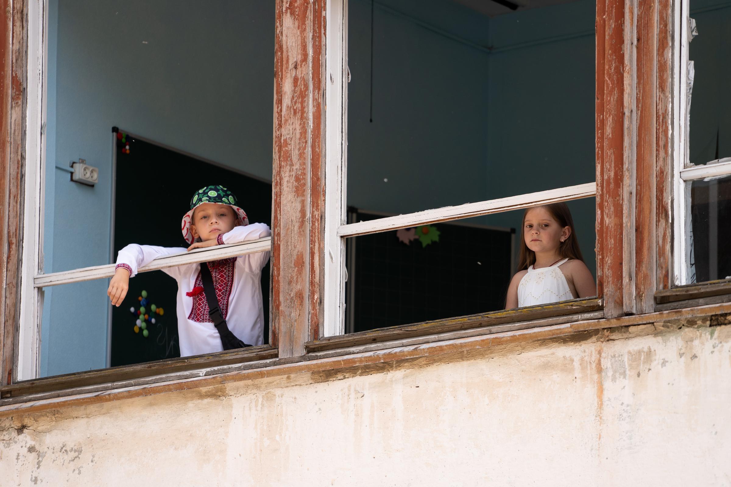 Zwei Kinder schauen aus einem Schulgebäude in der Ukraine. (Quelle: savED)